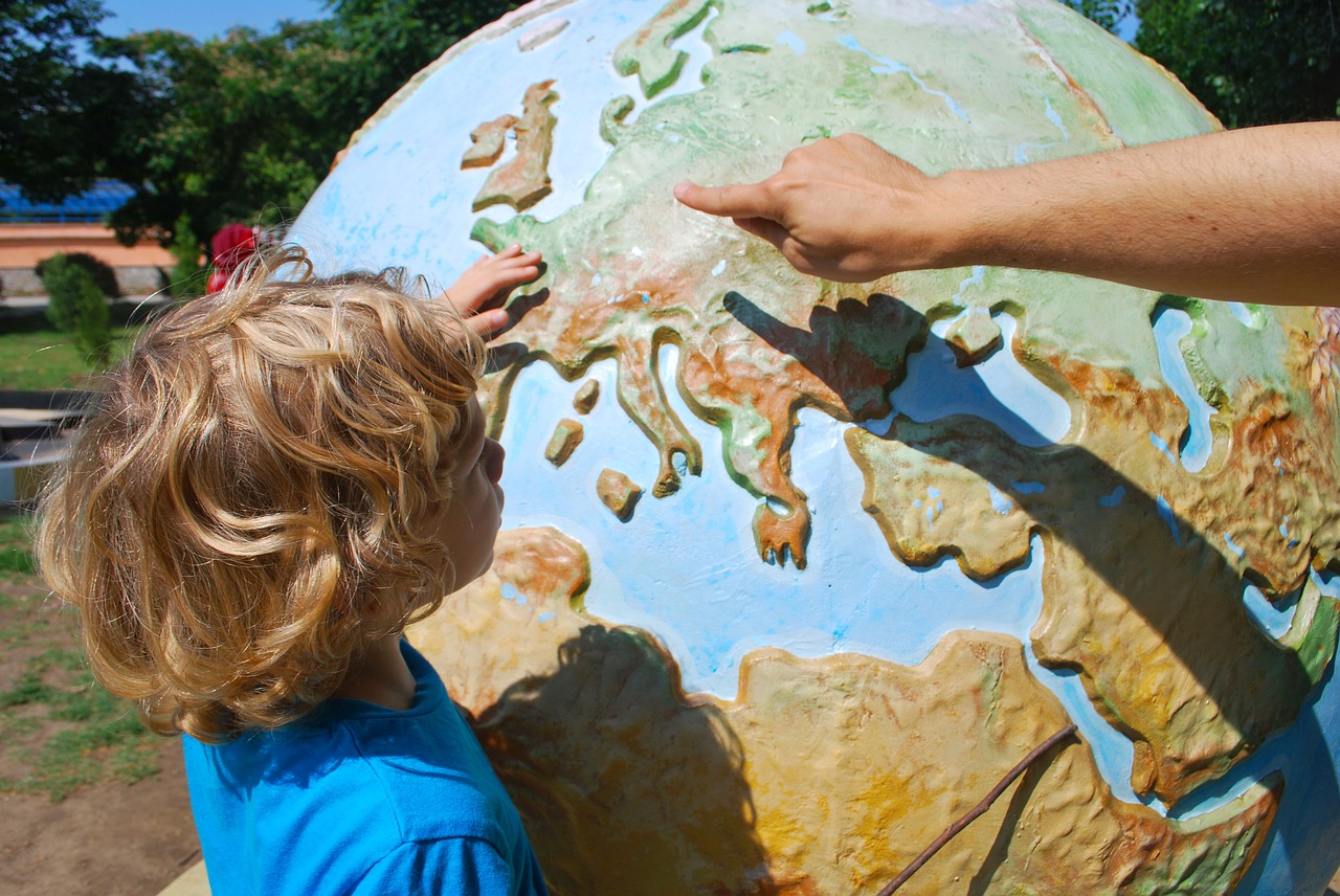Picture of a young boy in front of a large earth globe leaning about geography